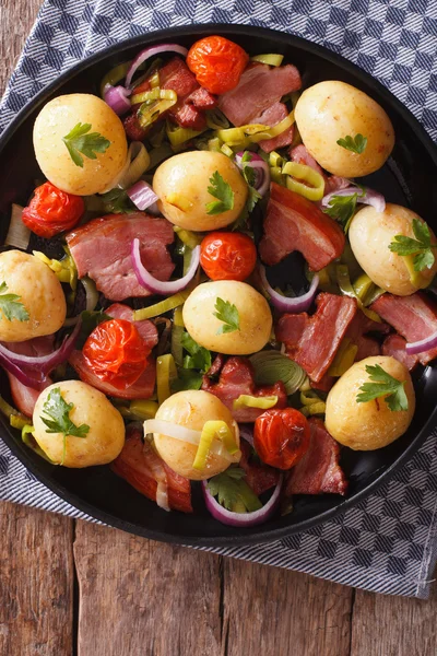 Tasty new potatoes with onion, tomato and bacon top view — Stock Photo, Image