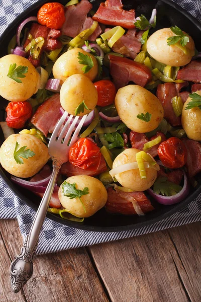 New potatoes with onions and bacon on a plate. Vertical, rustic — Stock Photo, Image