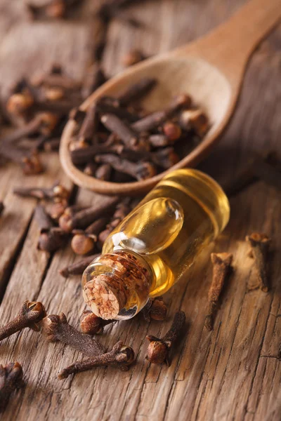 The essence of cloves in the bottle close-up. Vertical — Stock Photo, Image