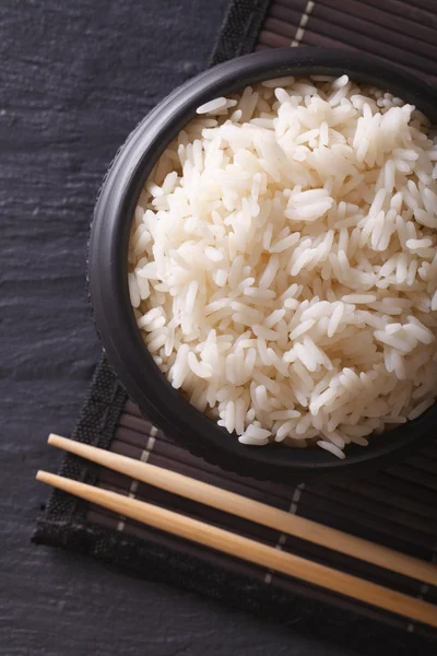 Arroz blanco en un tazón negro y palillos. vista superior vertical —  Fotos de Stock