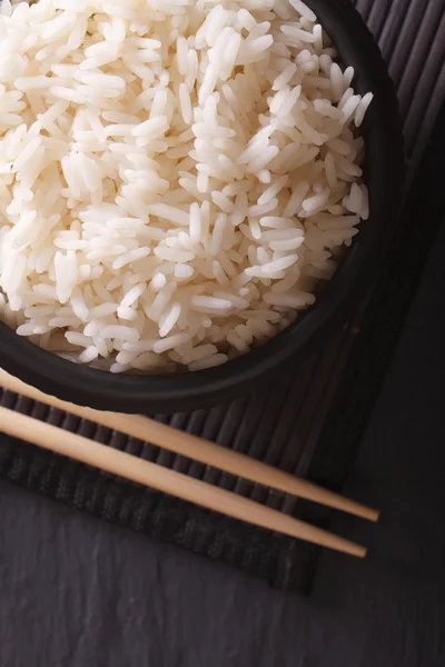 Delicioso arroz en un bol negro macro vista superior vertical —  Fotos de Stock