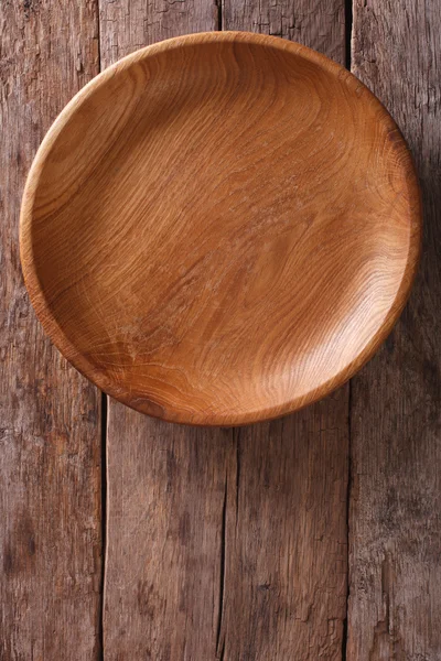 Wooden plate on a rustic table closeup. vertical top view — Stock Photo, Image