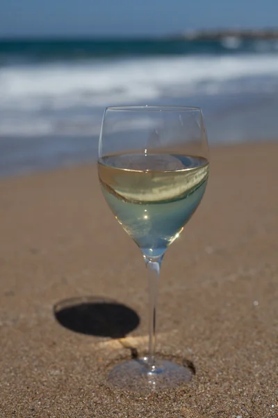 Um copo de vinho branco na areia da praia. Vertical — Fotografia de Stock