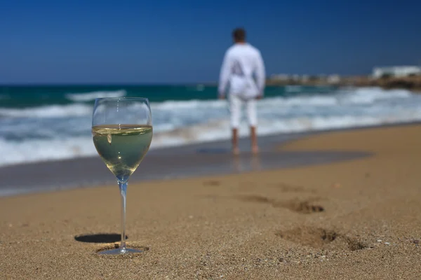 Homem perto do mar e um copo de vinho na areia — Fotografia de Stock