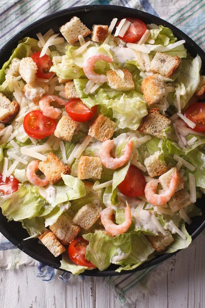 Fresh Caesar salad with shrimps closeup vertical top view — Stock Photo, Image