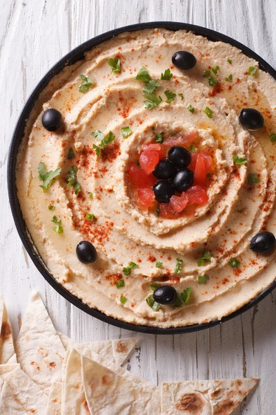 Hummus with olives, tomatoes and herbs vertical top view — Stock Photo, Image