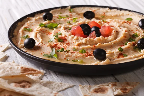 Hummus com azeitonas e ervas em uma chapa close-up. horizontal — Fotografia de Stock