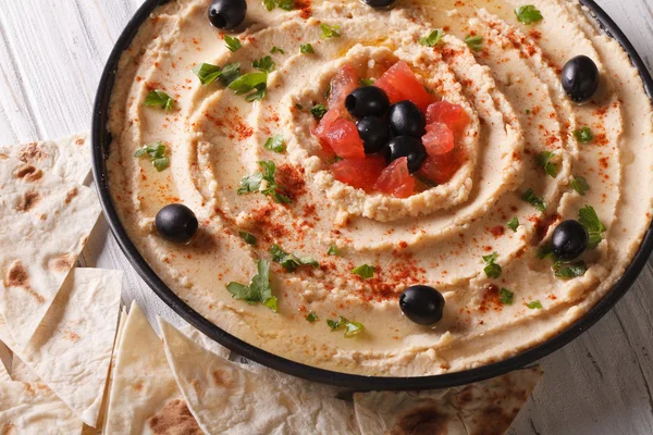 Hummus com azeitonas, tomates e ervas close-up. Horizontal — Fotografia de Stock