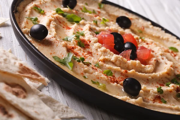 Хумус с оливками и помидорами на тарелке крупным планом . — стоковое фото