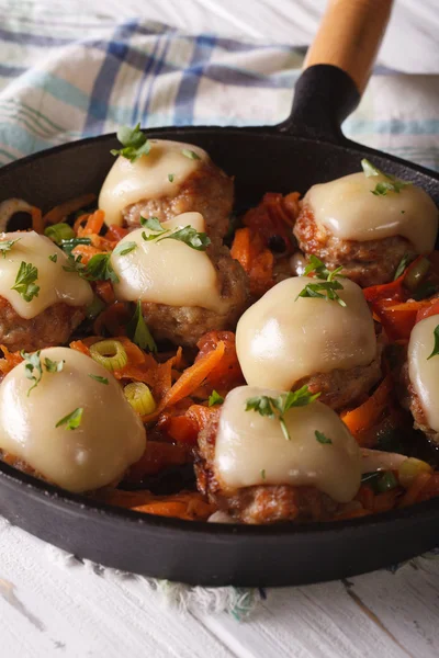 Meatballs baked with mozzarella close-up in a pan. Vertical