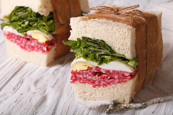 Sandwichs au salami et oeuf enveloppés dans du papier — Photo