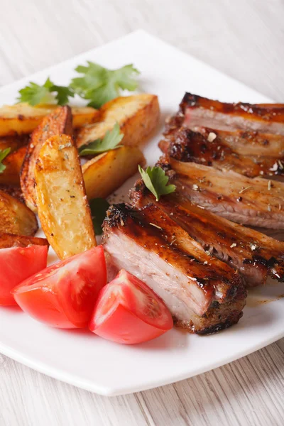 Roasted spareribs, potatoes and tomatoes closeup. Vertical — Stock Photo, Image