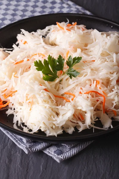 Sauerkraut und Karotten in einem schwarzen Teller in Großaufnahme senkrecht — Stockfoto