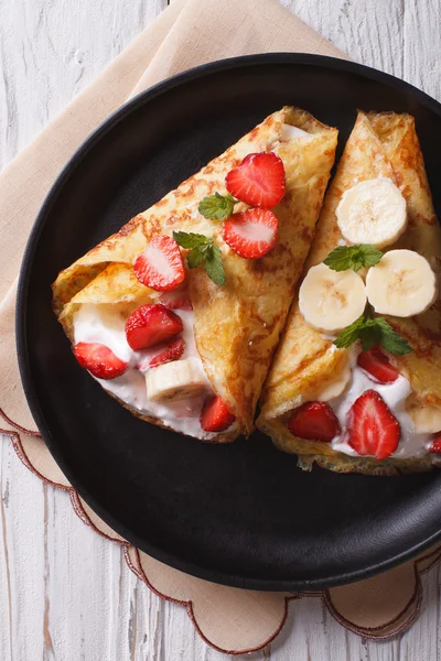 Crepes con fresas, plátanos y crema primer plano vertical —  Fotos de Stock