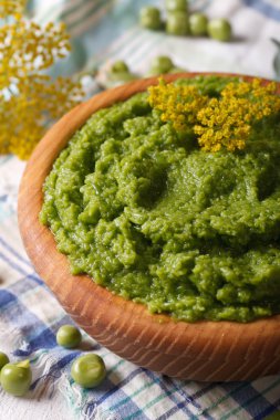 Puree of fresh green peas macro in a wooden bowl. Vertical clipart