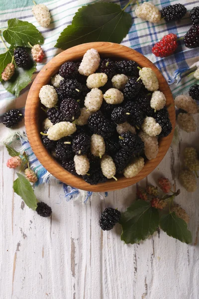 White and black mulberries in a wooden bowl vertical top view — Stock Photo, Image