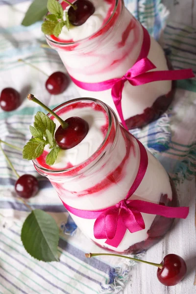 Whipped cream with ripe cherries in a glass jar top view — ストック写真