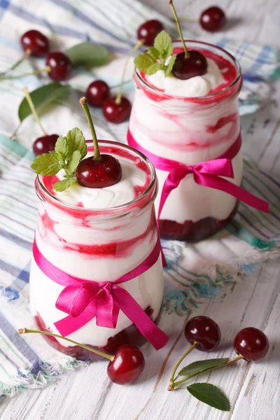 Yogurt con cerezas en un frasco de vidrio de primer plano en la mesa. verti — Foto de Stock