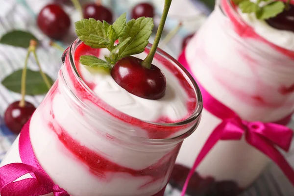 Soft cream with a cherry in a glass jar macro. horizontal — Stockfoto