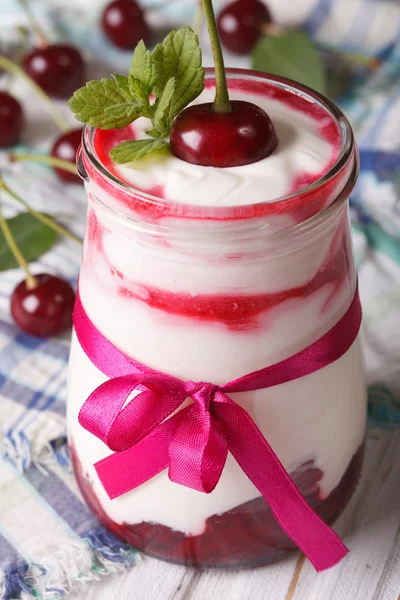 Delicious yogurt with cherry macro in a glass jar. vertical — Stock Photo, Image