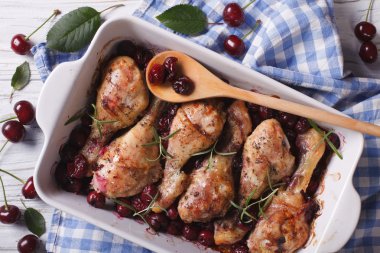 Baked chicken legs in cherry sauce in a dish horizontal top view
