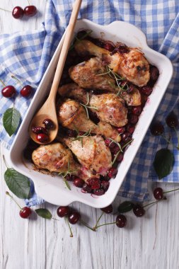 Baked chicken legs in cherry sauce in a dish vertical top view