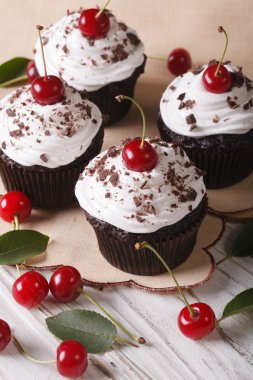 Beautiful chocolate cupcakes with white cream and cherry, vertic