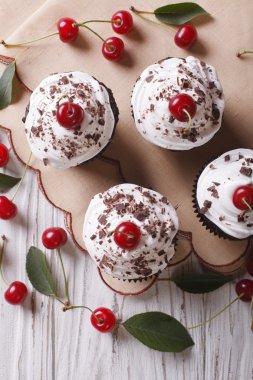 Chocolate cupcakes with cream and cherry close up vertical top v
