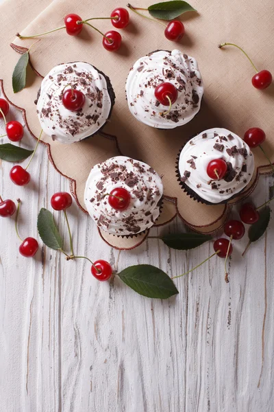 Chocolate cupcakes with cream and cherry vertical top view — Stock Photo, Image