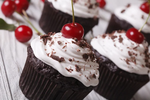 Bolinhos de chocolate fresco com creme e cereja de perto — Fotografia de Stock