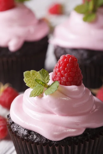 Schokoladen-Cupcakes mit rosa Sahne und Himbeer-Makro. vertikal — Stockfoto