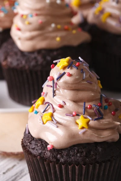 Beaux cupcakes au chocolat avec des bonbons saupoudrer macro. vertica — Photo