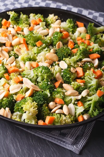 Broccoli with peanuts and carrots close-up vertical — Stock Photo, Image