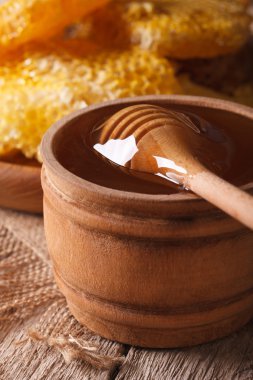 Flower honey in a wooden bowl with a stick close-up. vertical