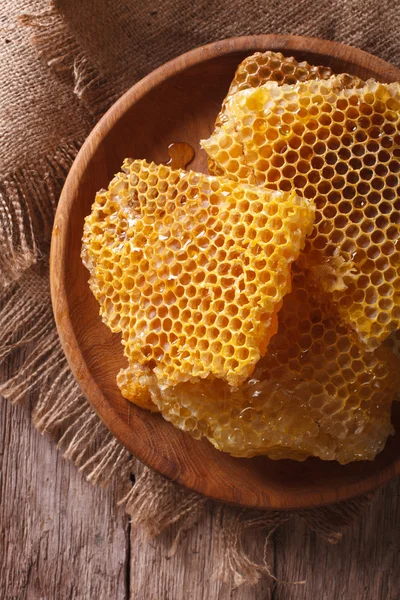 Des nids d'abeilles frais sur une assiette en bois close-up. vue de dessus verticale — Photo