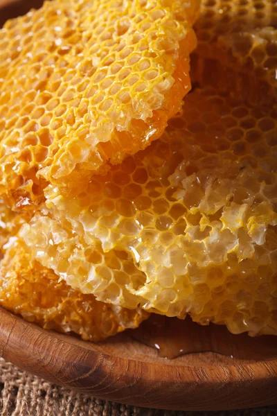 Fresh golden honeycomb on wooden plate macro. Vertical — Stock Photo, Image