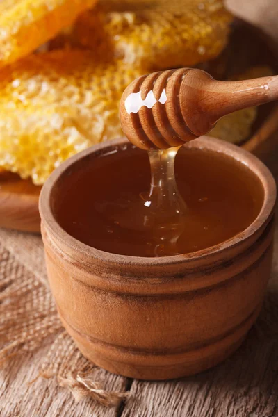 Mel líquido em uma tigela de madeira com um pau de perto. vertical — Fotografia de Stock