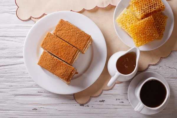 Honey cake, coffee, and a honeycomb. horizontal top view — Stock fotografie