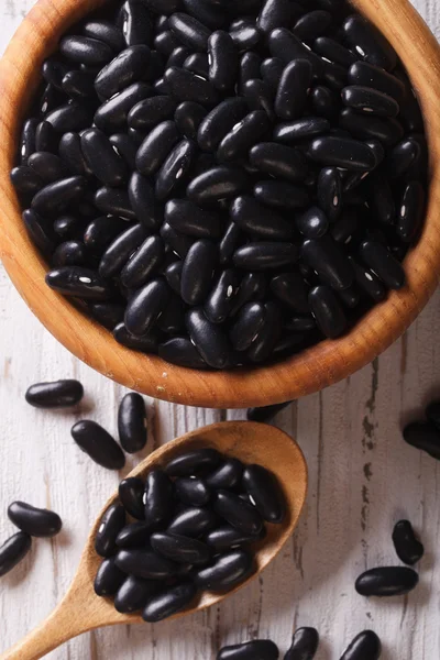 Black beans in a wooden spoon and a bowl macro. vertical top vie — Stock Photo, Image