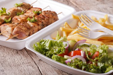 Fast food: kebabs, fries and fresh salad in tray close-up. horiz