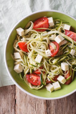 zucchini pasta with feta cheese and tomatoes closeup vertical to