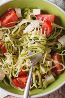 zucchini pasta with feta and tomatoes macro. vertical top view