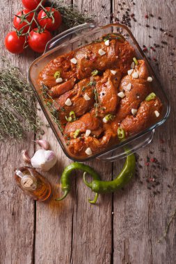 Meat in red marinade with spices in a bowl. vertical top view