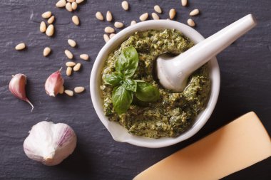 Igreen pesto in mortar and ingredients closeup. horizontal top v