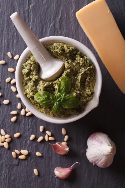 Pesto verde en mortero e ingredientes closeup.vertical vista superior — Foto de Stock