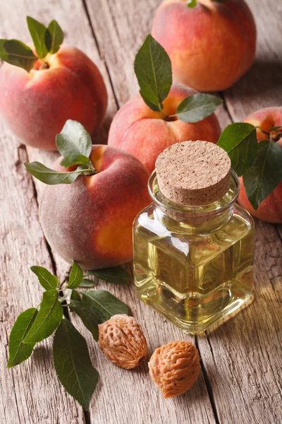 De natuurlijke olie van perzik steen in een fles close-up. verticale — Stockfoto