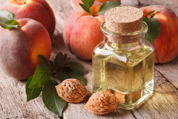 Pêssego de óleo cosmético em uma garrafa de vidro em uma mesa closeup. horizonte — Fotografia de Stock