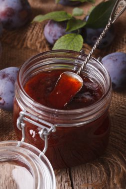 Delicious plum jam in a glass jar on the table close-up. vertica
