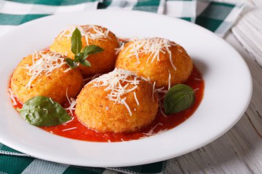 Delicious fried arancini rice balls in tomato sauce close-up. ho clipart