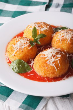 Delicious rice balls in tomato sauce on a plate close-up. vertic